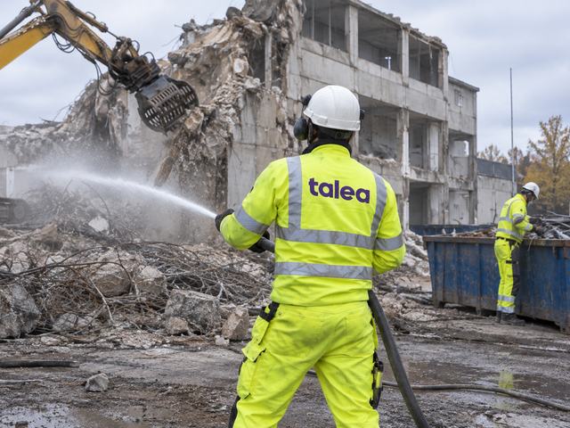 Talea-medarbetare dammbinder med vattenslang vid rivning av en industribyggnad