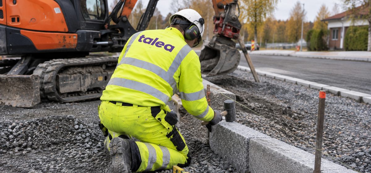 Anläggningsarbetare från Talea lägger kantsten intill en grävmaskin