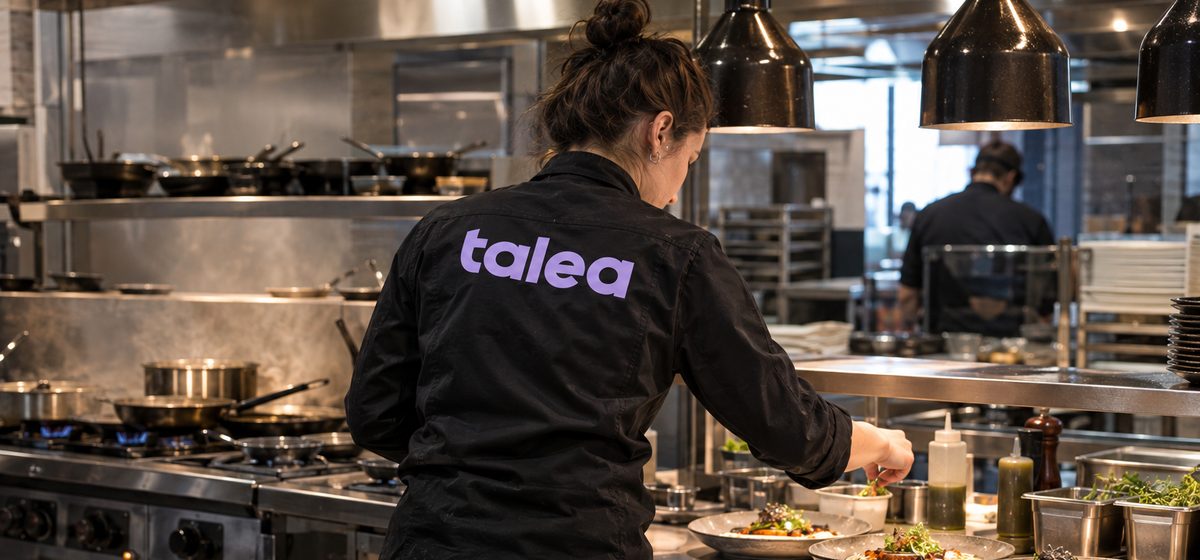 Kock från Talea i svart kockjacka lägger upp rätter vid passet i ett restaurangkök