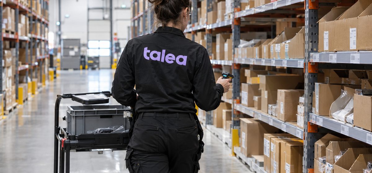 Orderplockare från Talea i svarta arbetskläder plockar med handdator i ett e-handelslager