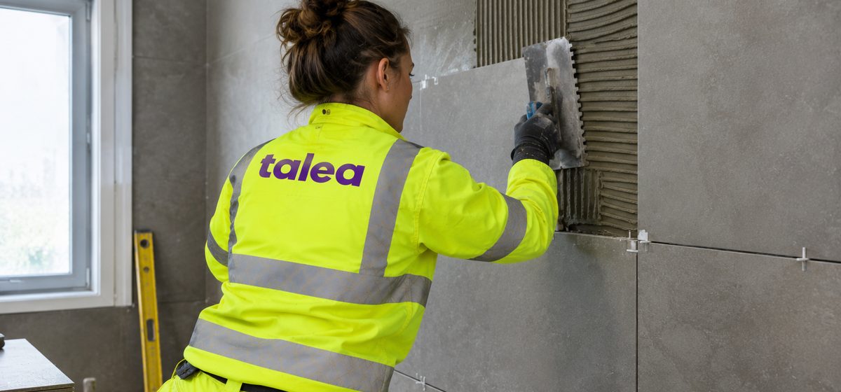 Plattsättare från Talea sätter stora klinkerplattor på en badrumsvägg