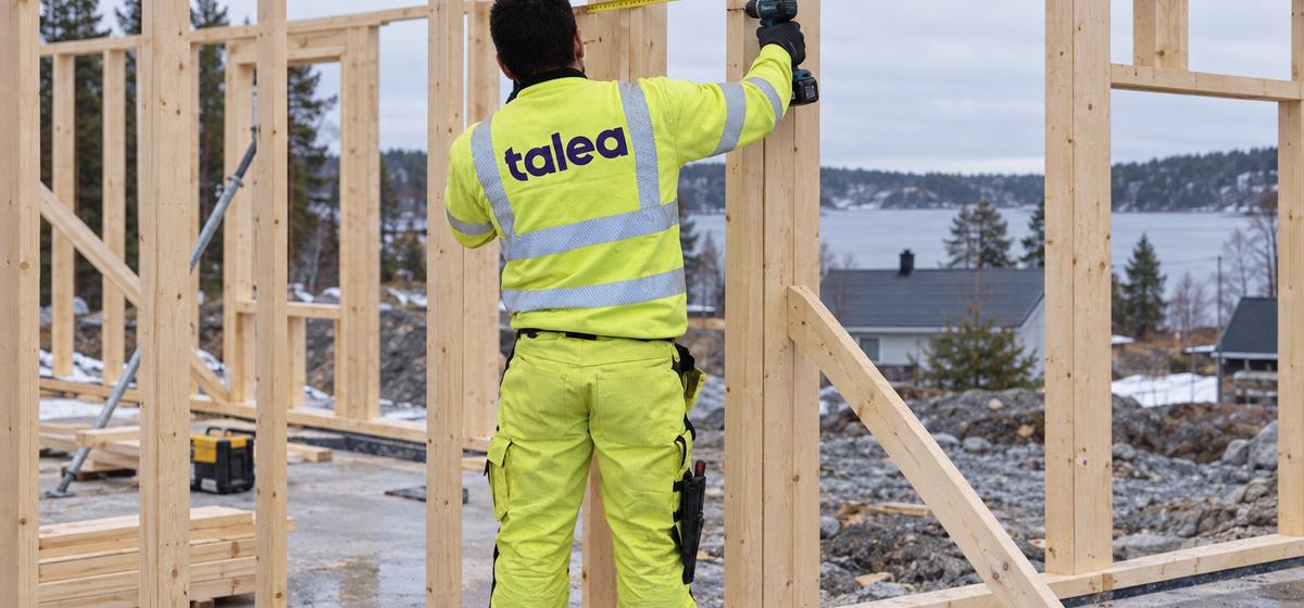 Talea-snickare mäter och skruvar i en regelstomme