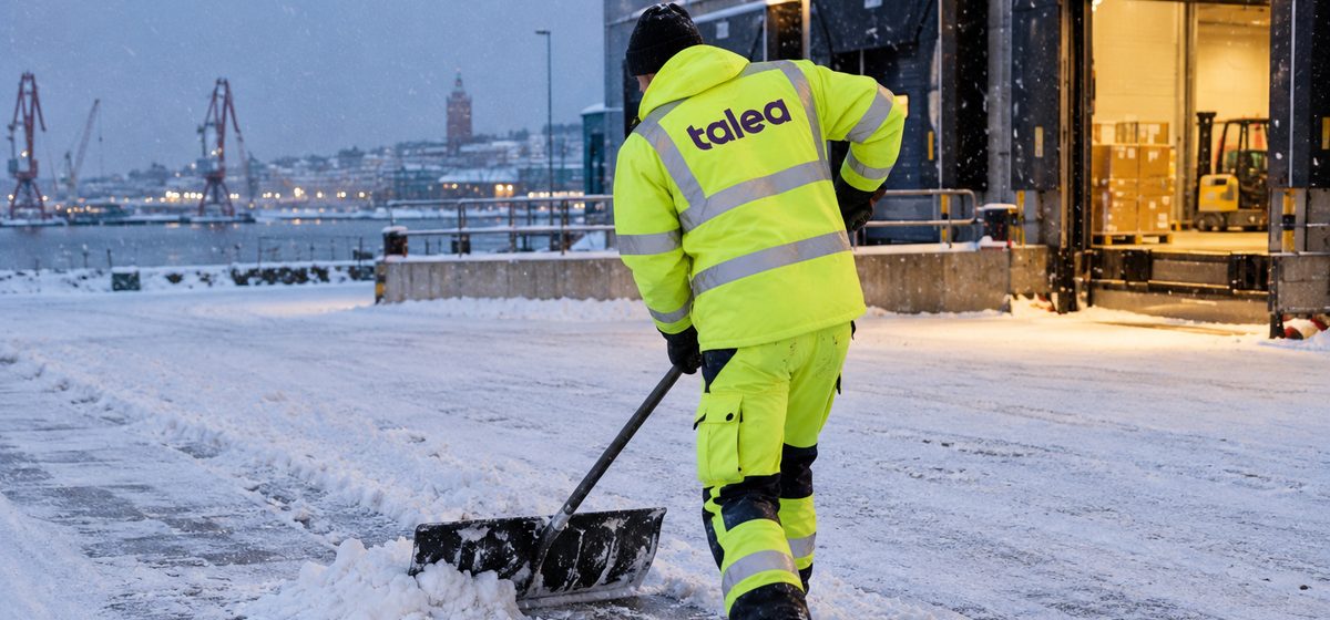 Talea-medarbetare i varseljacka röjer snö på en lastgård i Göteborg