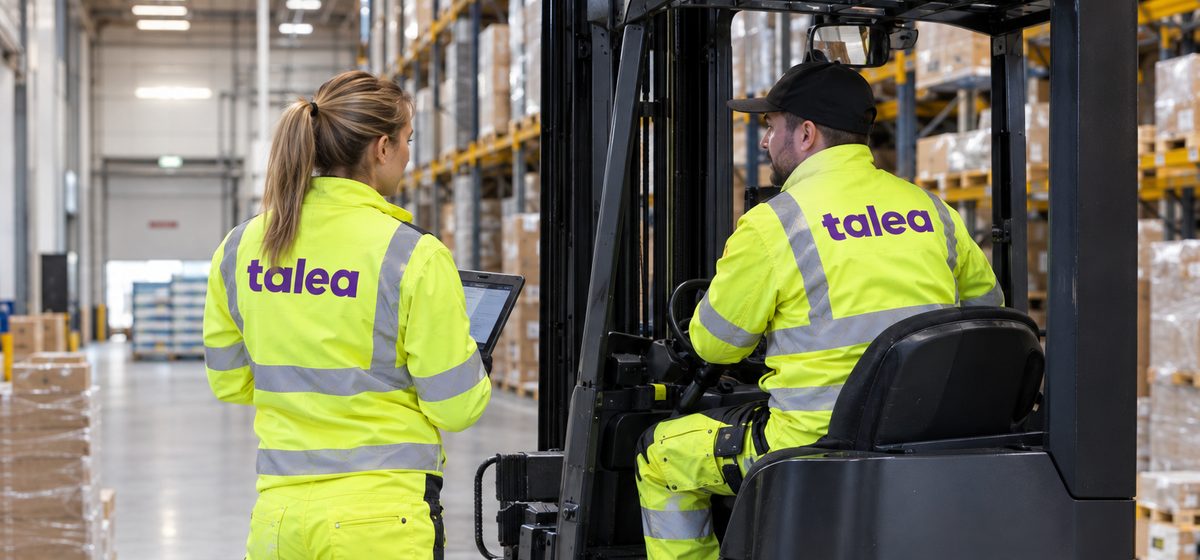 Teamledare från Talea med surfplatta pratar med en truckförare i ett höglager